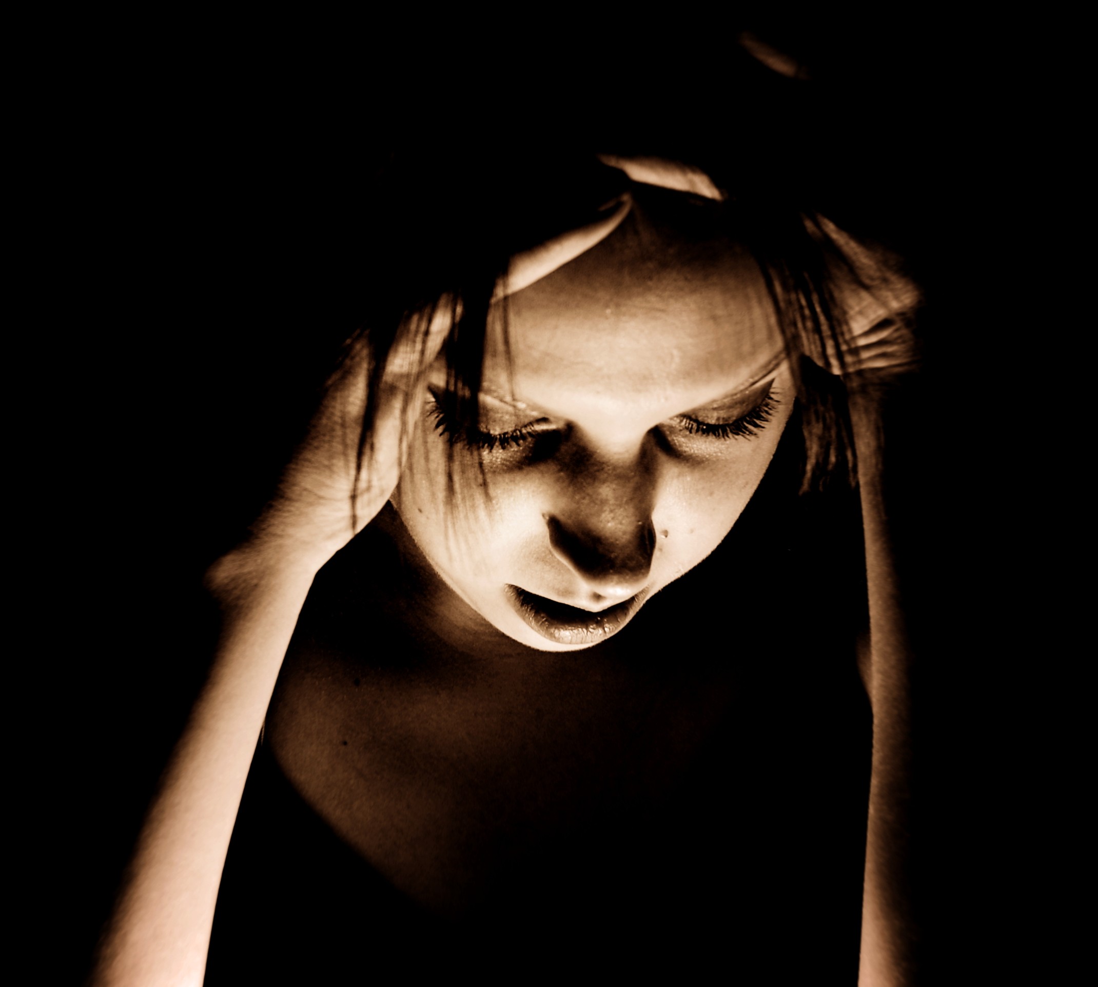 Woman suffering from a migraine in a dark room.